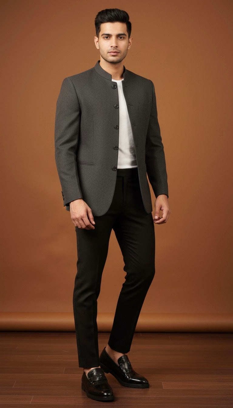 Man wearing a gray blazer, white shirt, black pants, and black shoes against a brown background