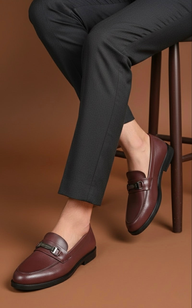 Person wearing brown loafers and dark pants on a brown background