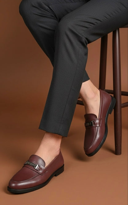 Person wearing brown loafers and dark pants on a brown background