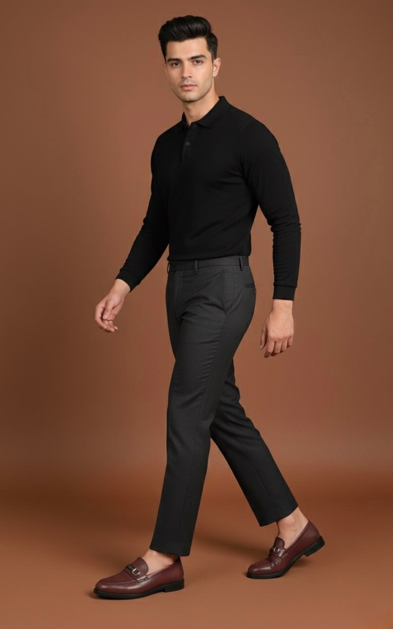Man wearing a black shirt and dark pants against a brown background