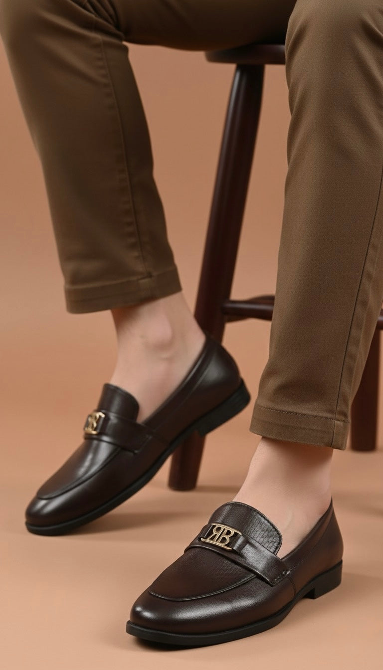Brown leather loafers worn with beige pants on a brown background