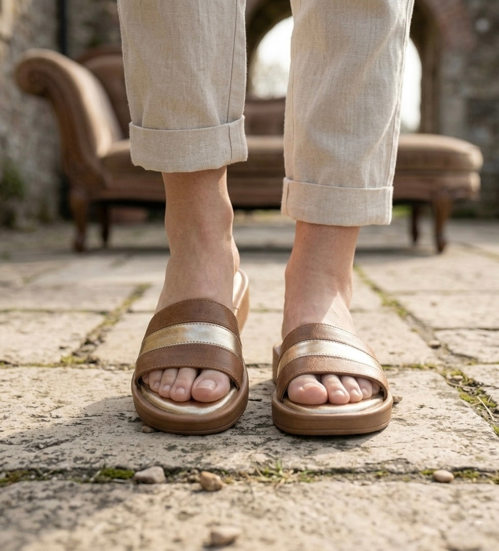 Person wearing brown sandals on a stone pavement with a blurred background