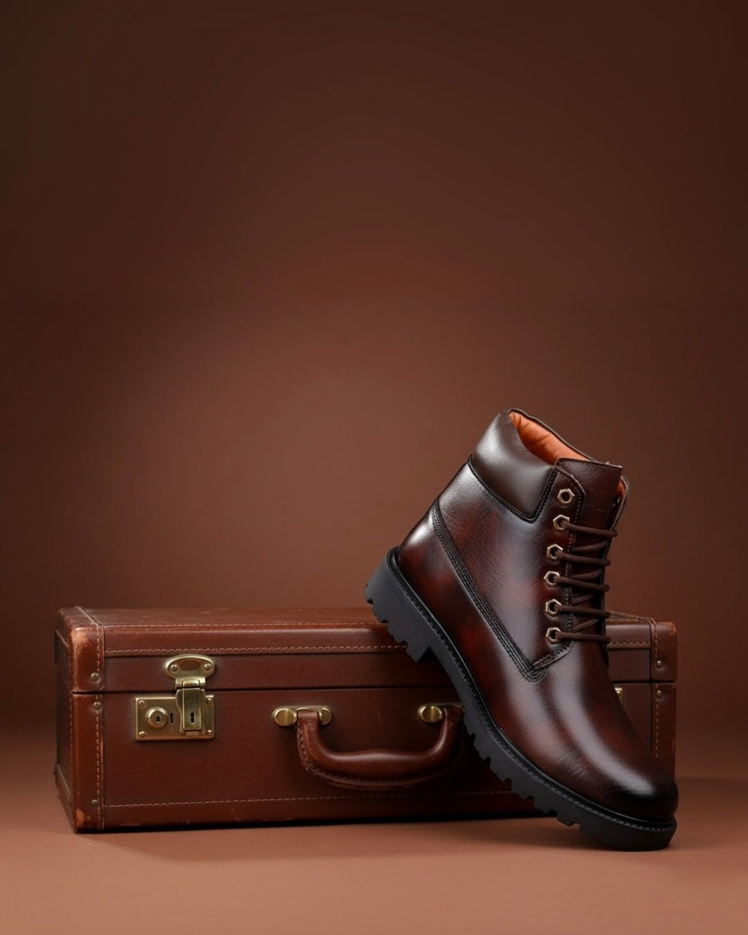 Brown leather boot and vintage suitcase on a brown background