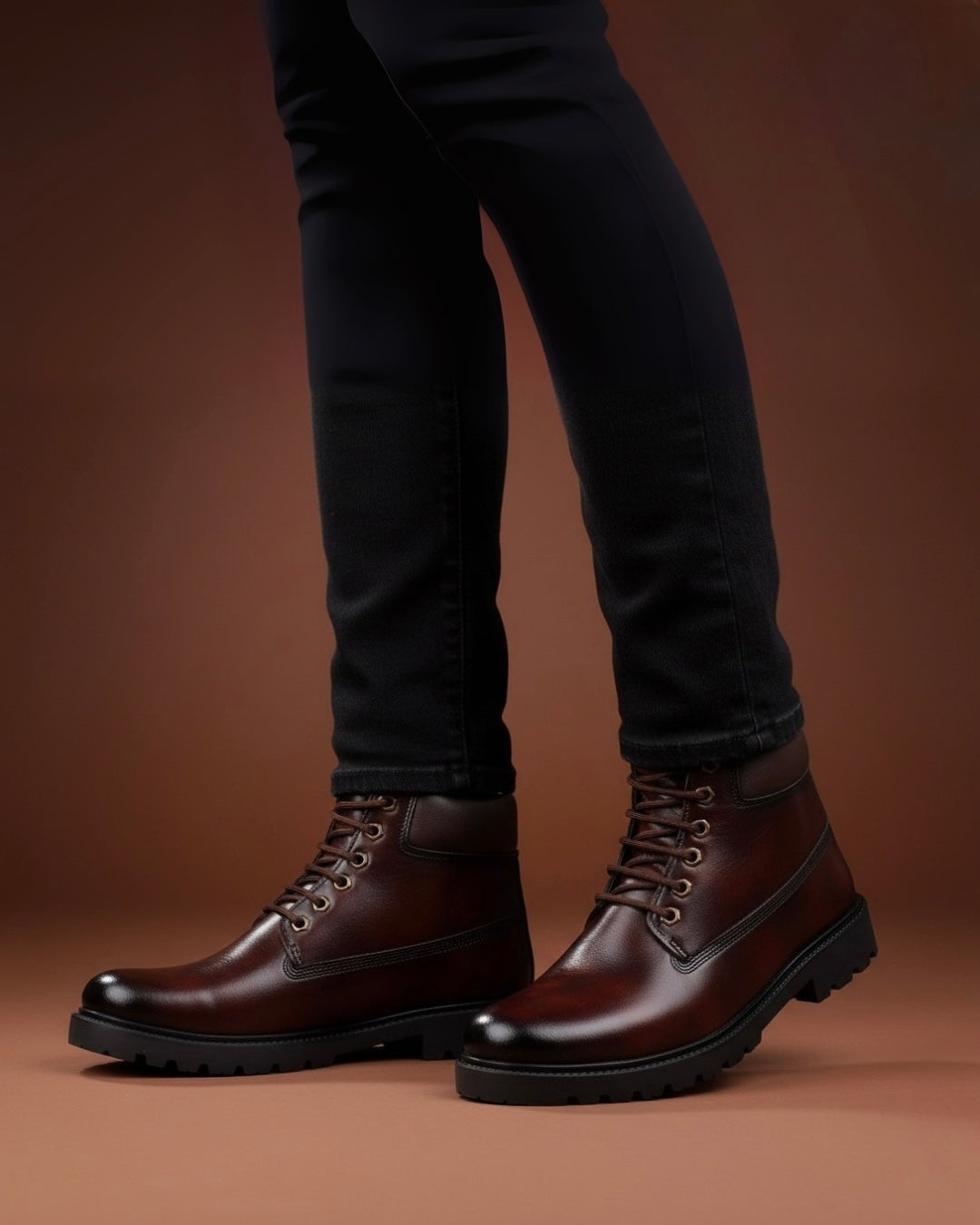 Brown leather boots worn with black pants on a brown background