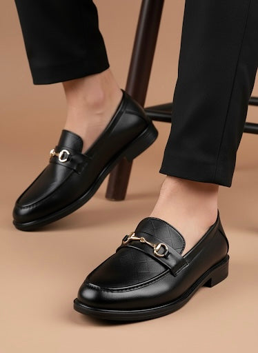 Black leather loafers worn with black pants on a beige background