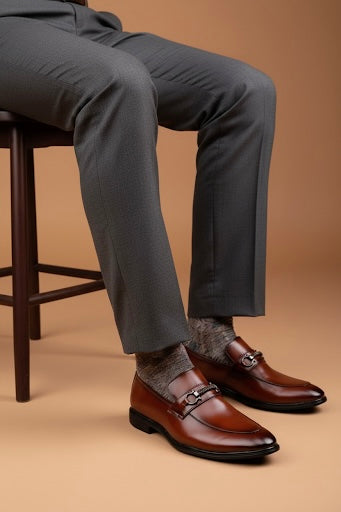 Person wearing brown dress shoes and gray pants on a beige background