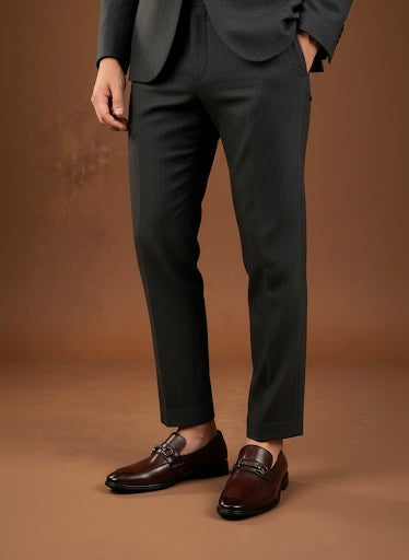 Person wearing a dark suit and brown shoes on a brown background
