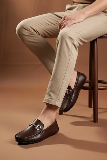Brown leather loafers worn with beige pants on a brown background