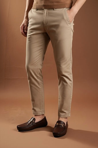 Person wearing beige pants and brown loafers on a brown background