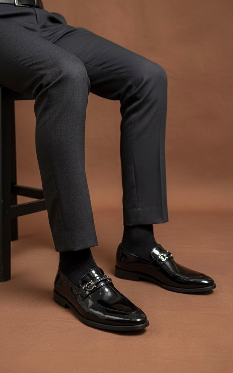 Person wearing dark gray pants and black shoes on a brown background