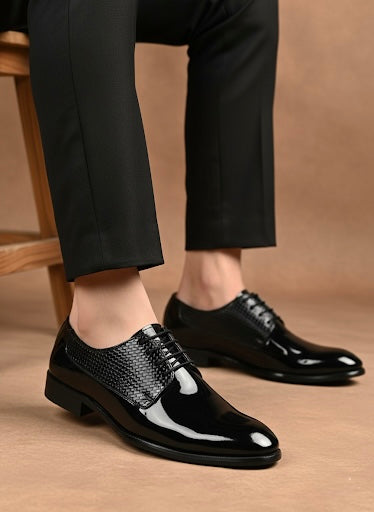 Black dress shoes with metallic accents worn with black pants on a brown background